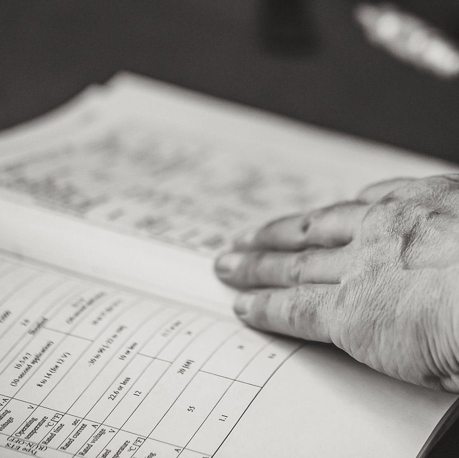 A machinist's hand rests on an open reference book.